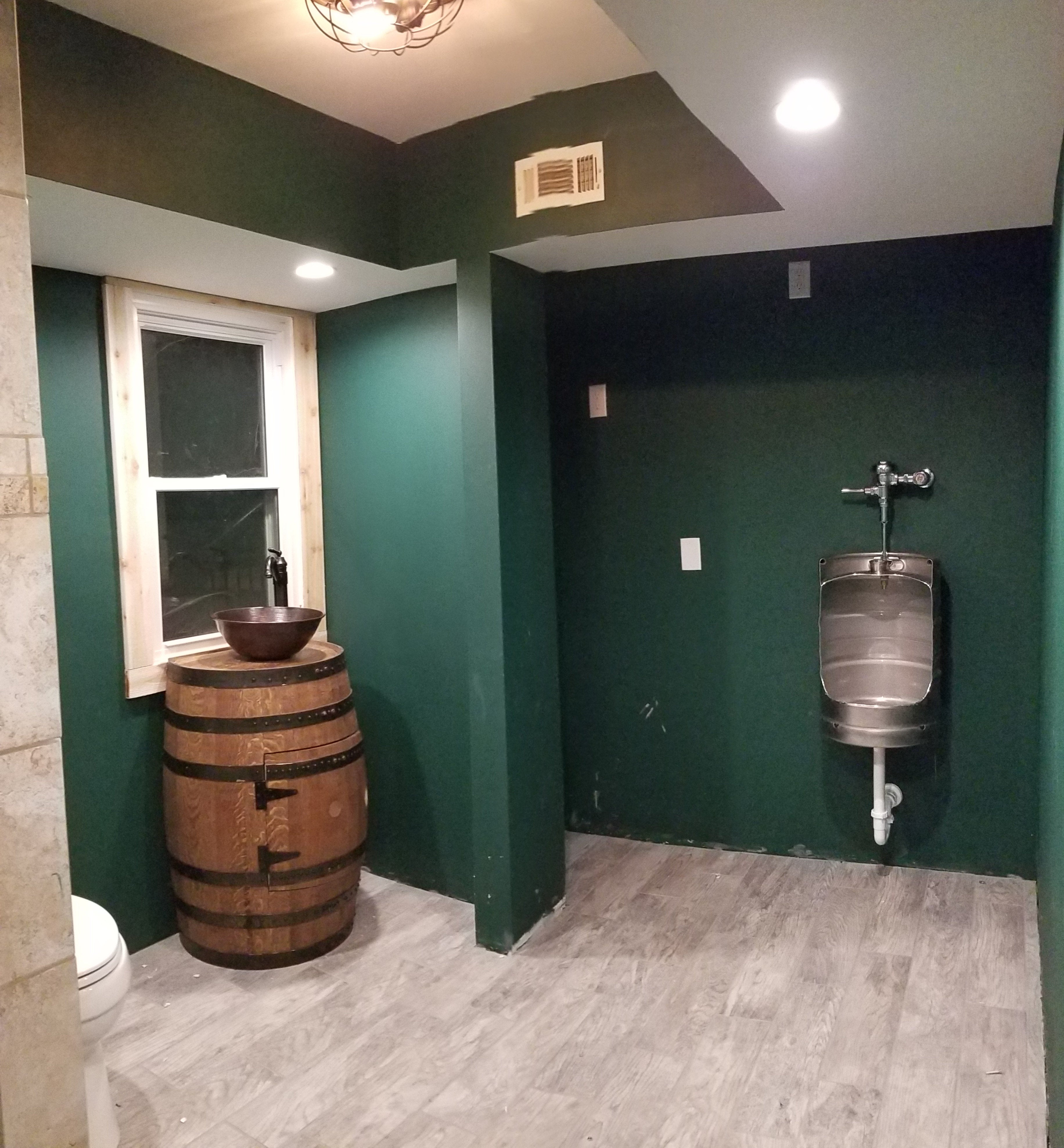 Bathroom with green walls, wooden barrel sink, and keg urinal.