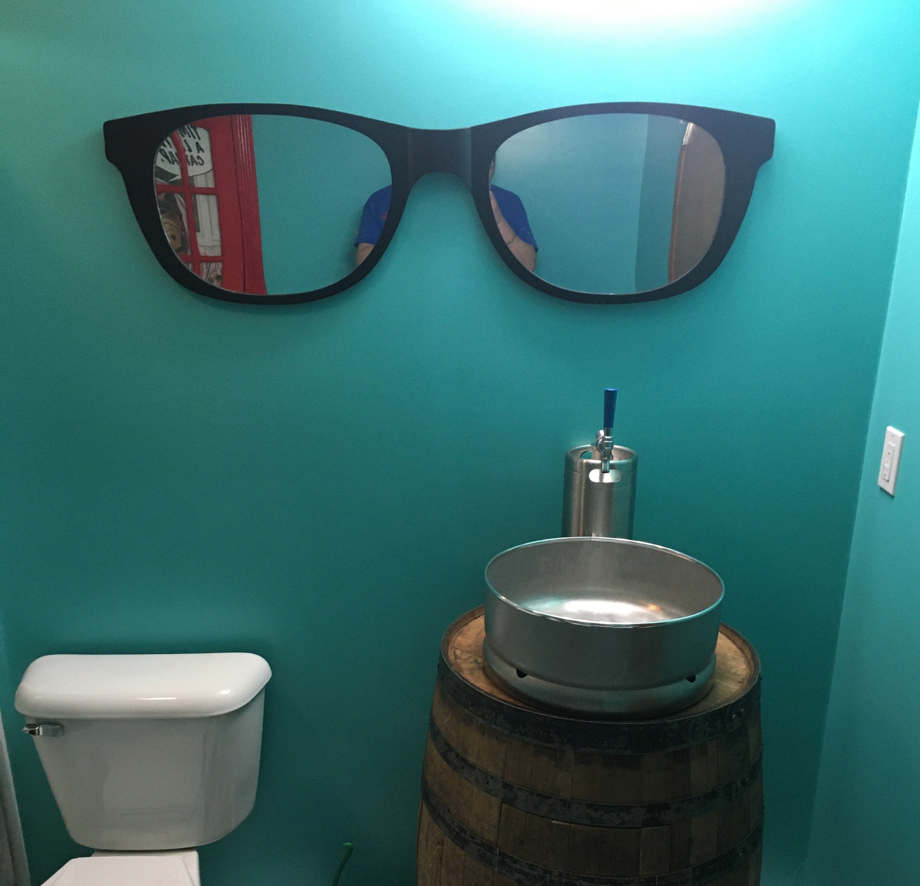 Bathroom with teal walls, a toilet, and a unique keg sink on a wooden barrel.